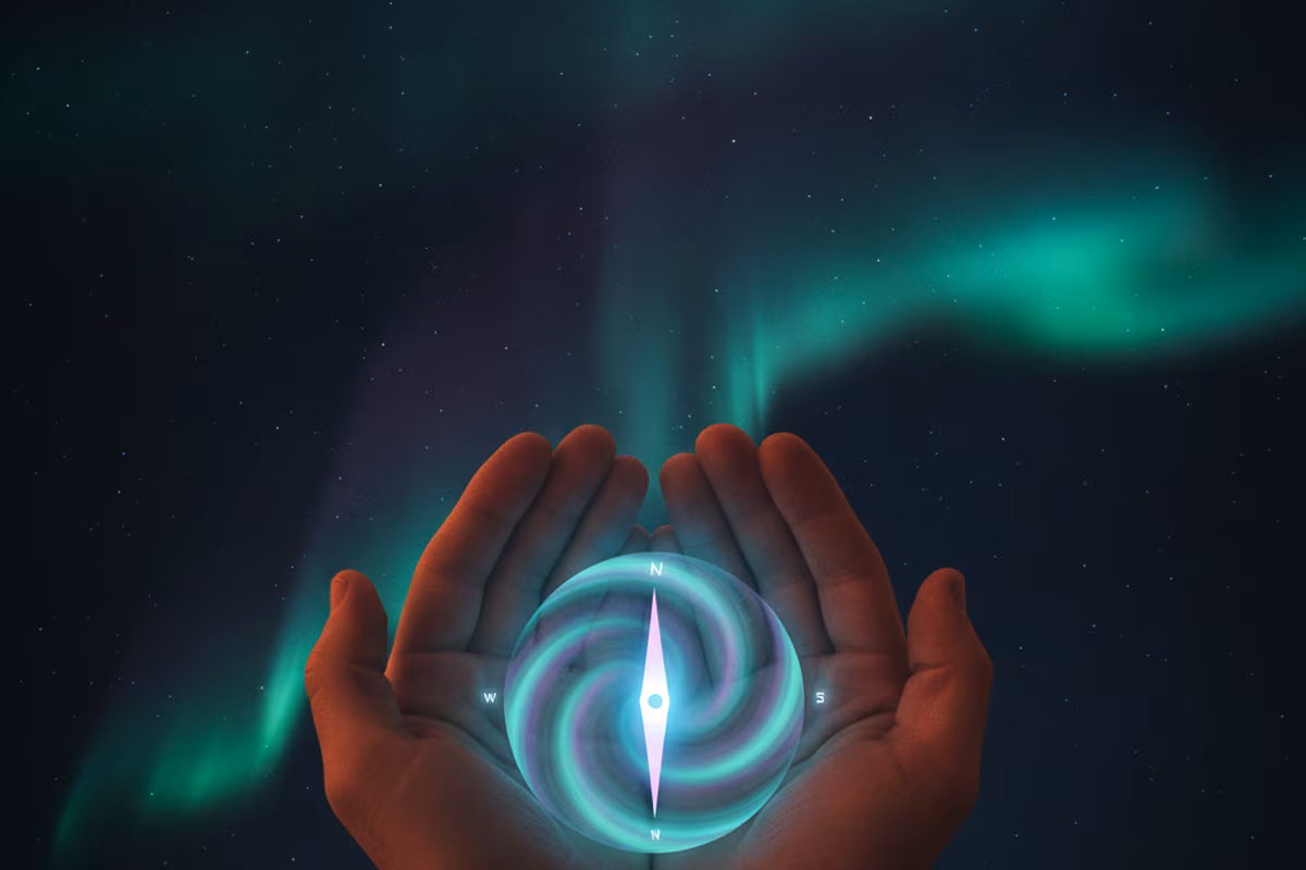 Glowing aurora compass held in cupped hands under a northern sky
